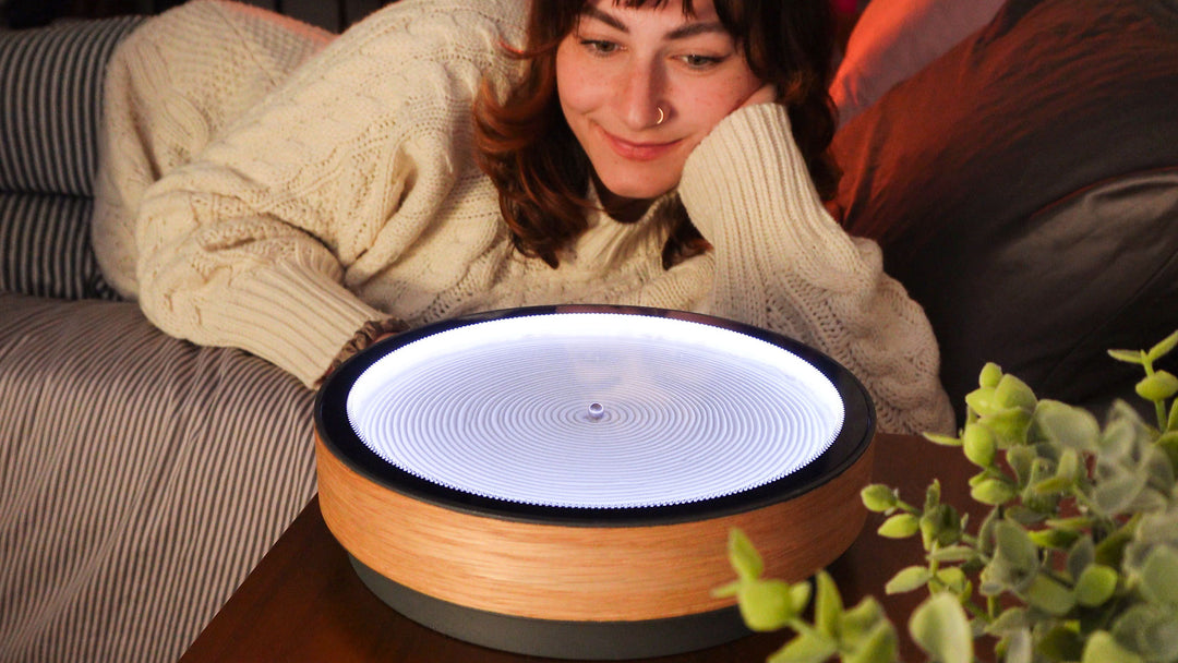 Oasis Mini trên bàn cạnh giường ngủ trong khi một cô gái bình tĩnh quan sát